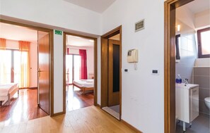 Ein Hotelzimmer mit Holzboden, einem Bett, einem Schreibtisch mit Stuhl und einem Badezimmer mit Waschbecken und Toilette.