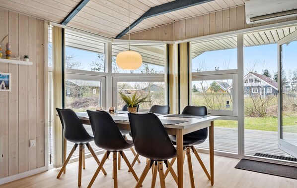 Un comedor con mesa de madera, sillas negras y una lámpara colgante.