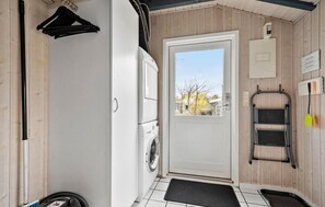 A laundry room with a washing machine, a drying rack, and a door leading to an outdoor area.