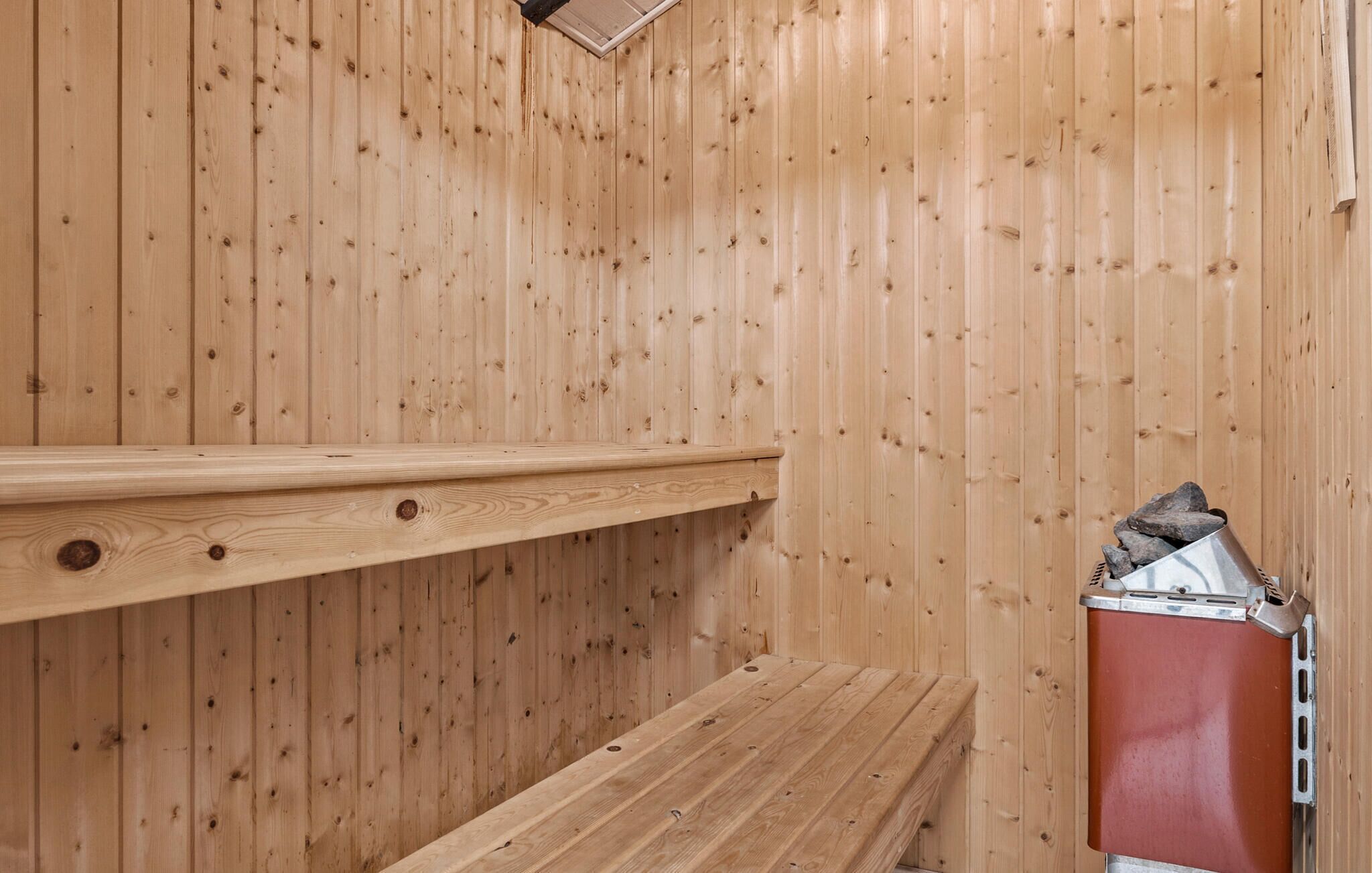 Een houten sauna met banken en een sauna-oven.