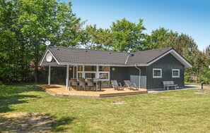 Une maison de plain-pied dotée d’un patio couvert, d’une terrasse et d’un petit jardin.