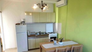 Une cuisine compacte équipée d’un réfrigérateur, d’une cuisinière et d’un évier, ainsi qu’une table à manger avec des chaises et un lustre.