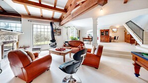 Un vaste salon doté d’une cheminée, de canapés en cuir, d’un coin repas et d’un escalier.