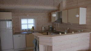 Eine kleine Küche mit Holzausstattung, einem Kühlschrank, einer Spüle und einem Fenster.