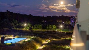 Ein Hotel bei Nacht mit Schwimmbad, beleuchteten Wegen und bewaldeter Umgebung.