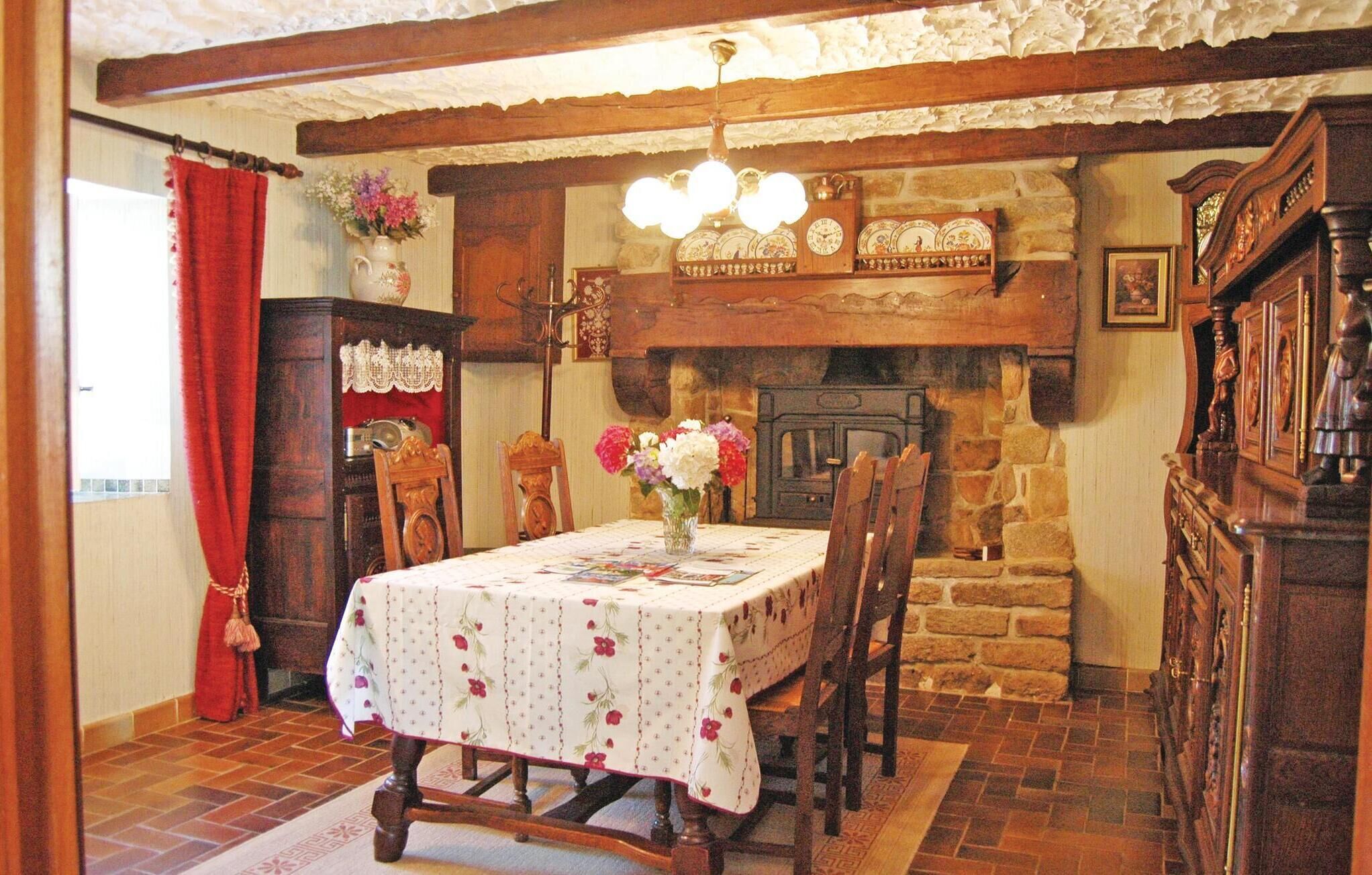 A dining room with a stone fireplace, wooden furniture, and a chandelier.