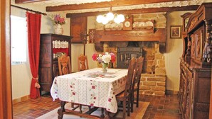 Uma sala de jantar com lareira de pedra, mobiliário de madeira e um candelabro.