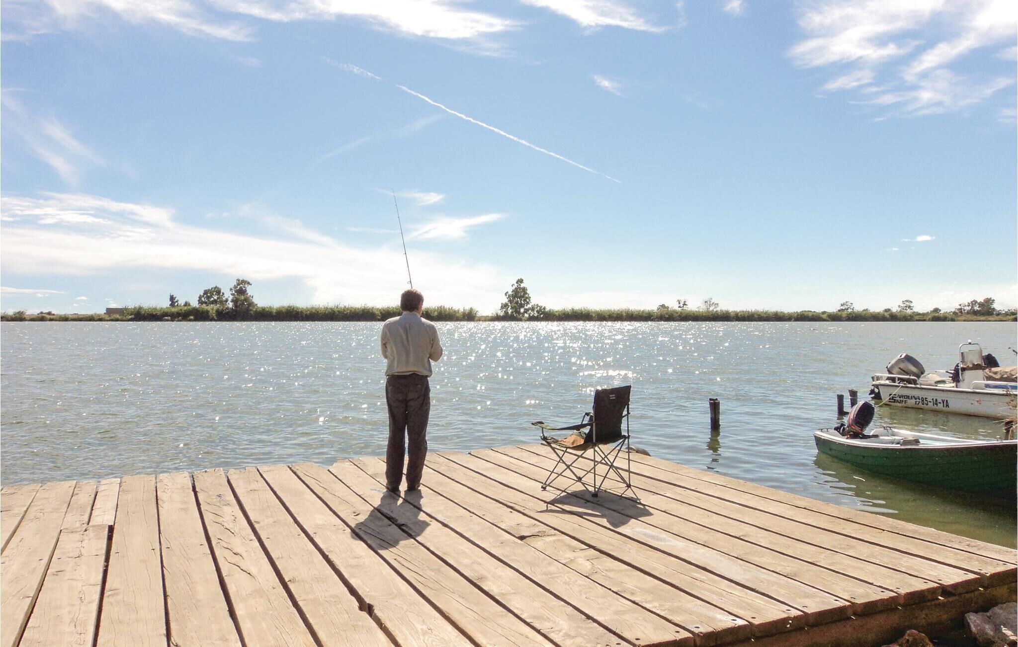 A wooden dock extending into a calm body of water with a clear sky.