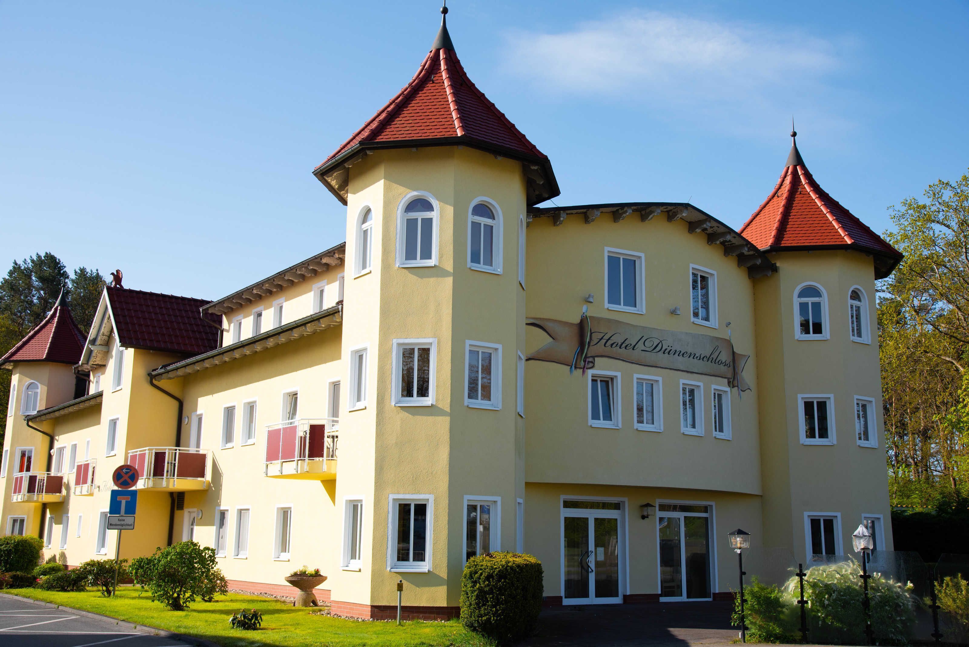 A multi-story hotel with a yellow facade, red roof, and balconies.