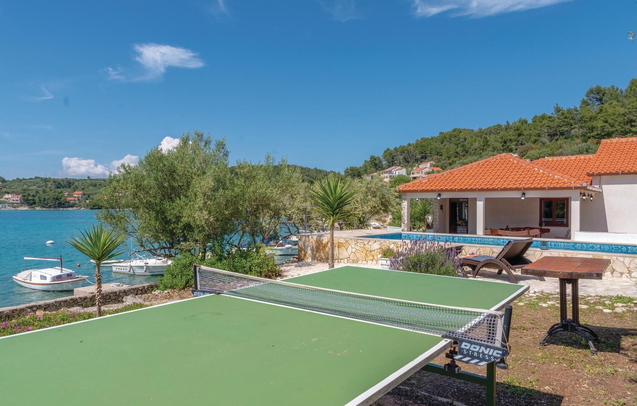 A pool table and outdoor seating area with a view of the sea and houses in the background.