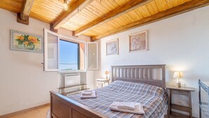 Une chambre à coucher avec un lit en bois, une fenêtre donnant sur un beau paysage, un radiateur et une table de chevet avec une lampe.