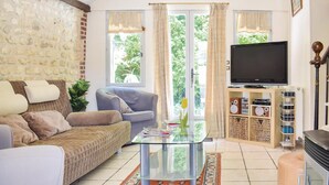 Un salon comprenant un canapé, des fauteuils, une table basse en verre, un téléviseur et une cheminée.