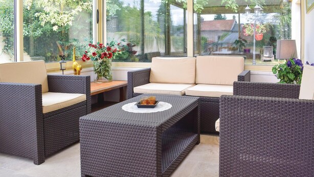 Un espace extérieur moderne, aménagé avec des meubles en osier, un canapé confortable et une table basse.