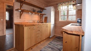 A wooden cabin kitchen with a central island, wooden cabinets, a refrigerator, and a window with curtains. - 3 bedroom beautiful home in årjäng (Årjäng)