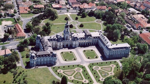 Luchtbeeld van een groot, historisch gebouw met symmetrische tuinen en een centrale fontein.