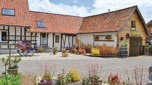 En traditionel europæisk bygning med tegltag, træhegn og en grusbelagt gårdsplads.