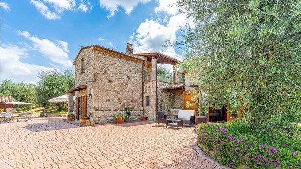 A stone building with a patio area, outdoor seating, and a garden with purple flowers. - Gorgeous home in Seggiano GR with house a panoramic view (Seggiano GR)
