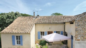 Un bâtiment de style rustique, doté d’un toit en tuiles, d’un petit patio avec des sièges extérieurs et d’une cheminée.
