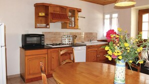 Une cuisine avec des meubles en bois, un four à micro-ondes, un grille-pain, un évier et une table à manger agrémentée d’un vase de fleurs.