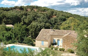 Una villa con piscina, rodeada de exuberante vegetación y montañas al fondo.