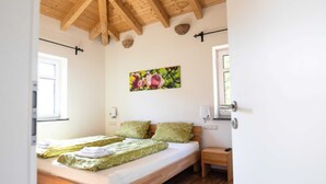 Un dormitorio con cama de madera, una mesita de noche, una lámpara de pared y una ventana con vistas a zonas verdes.