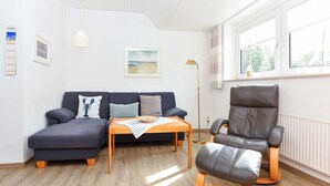 Een moderne woonkamer met een bank, een salontafel, een leren fauteuil en een vloerlamp.