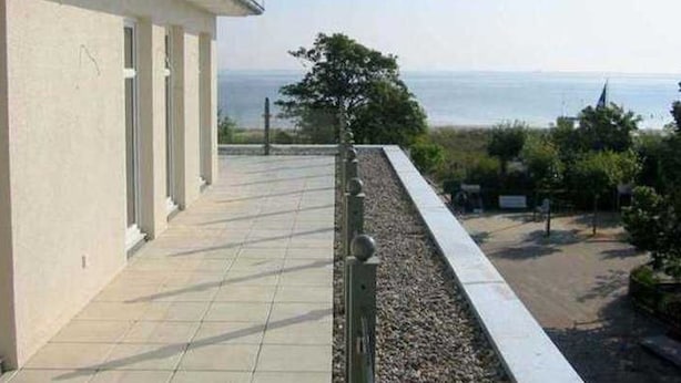 A building with a tiled balcony overlooking a body of water.