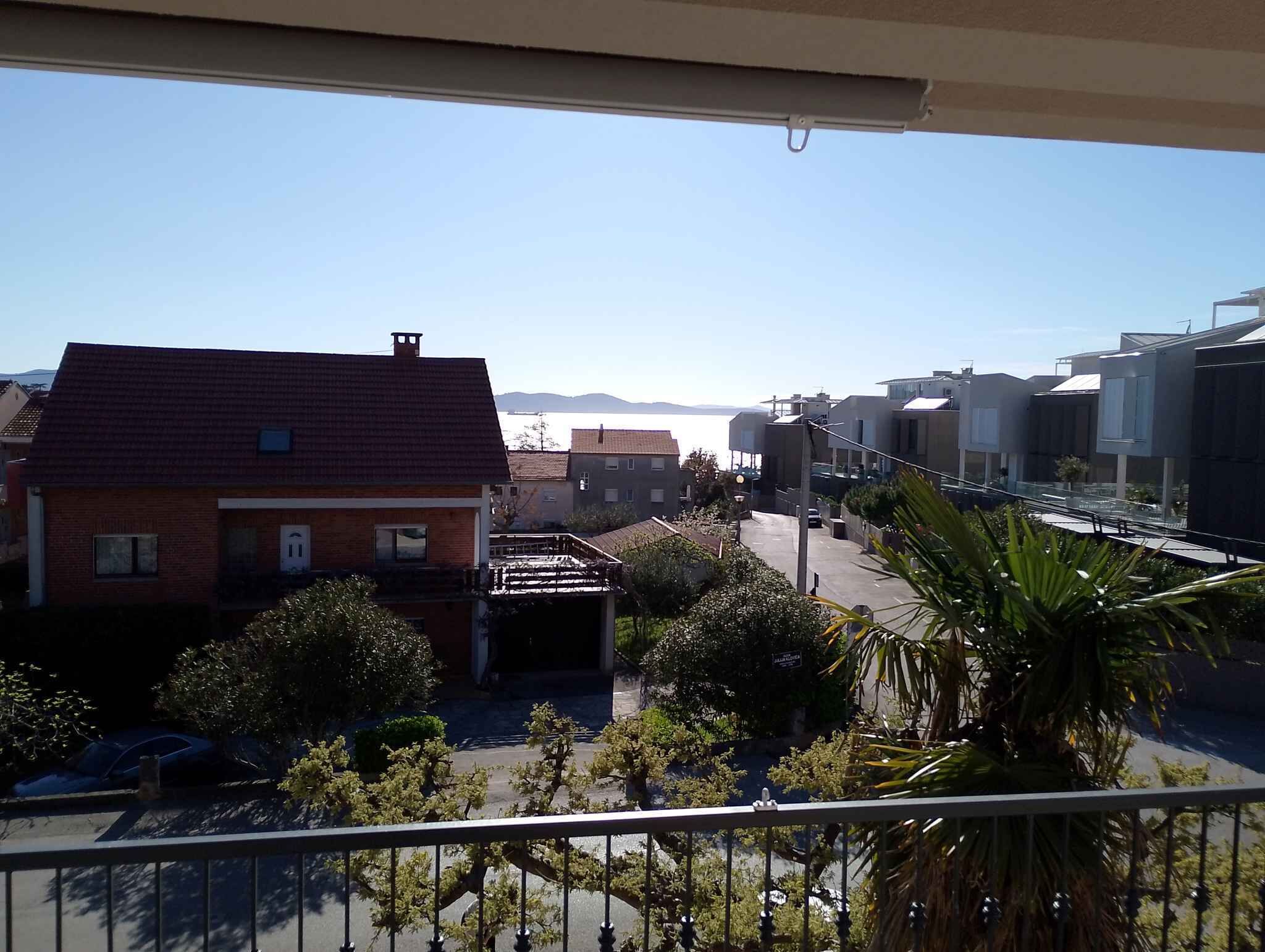 Un barrio residencial con casas, cielo despejado y vista al mar.
