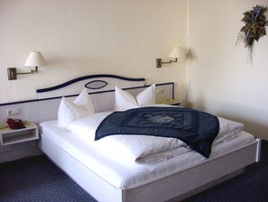 A hotel room with a bed, two bedside tables, a lamp on each table, and a wall-mounted light fixture. - 28 Blaudruckzimmer - Country Hotel (Elsterheide)