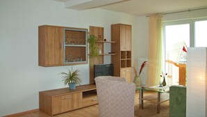 Een moderne woonkamer met houten kasten, een glazen salontafel en een comfortabele fauteuil.