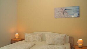 Een slaapkamer met een bed, twee nachtkastjes en een kunstwerk aan de muur.