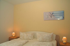 A bedroom with a bed, two bedside tables, and a wall-mounted artwork.