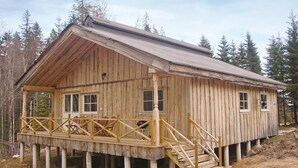 Eine Holzhütte mit Veranda, mehreren Fenstern und einer Treppe zum Eingang.