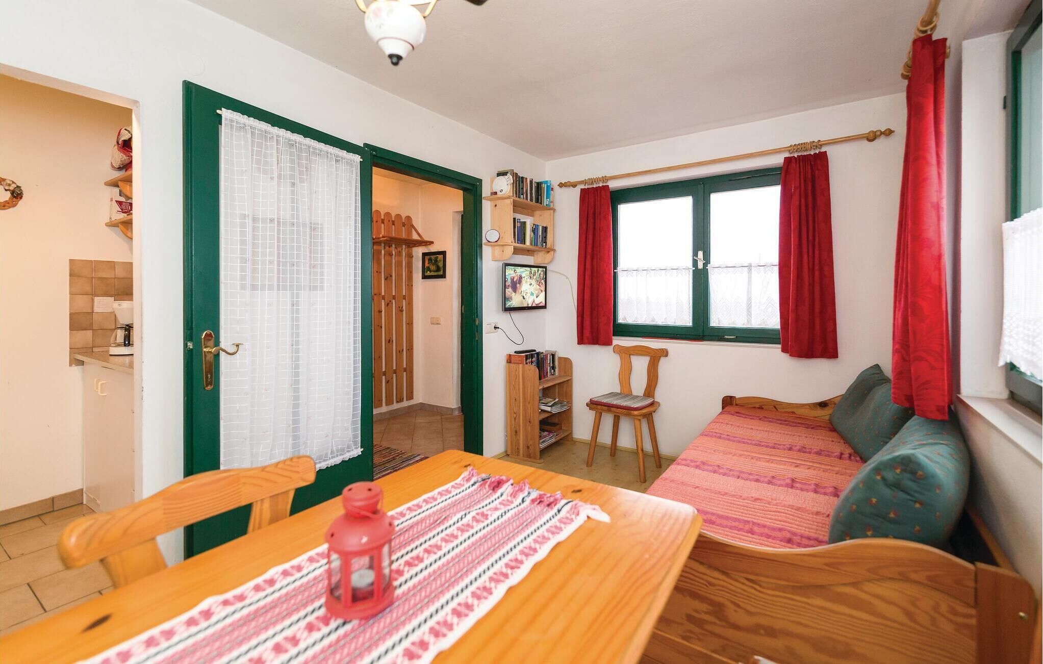 Una habitació acollidora amb una taula de fusta, un sofà verd i una finestra amb cortines vermelles.