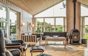 Amplia sala de estar con chimenea, muebles de cuero y grandes ventanales que ofrecen vistas al exterior.