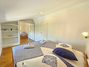 A bedroom with two beds, a wardrobe, a shelf with books, and a mirror. - Holiday apartment with garden and air conditioning (Crikvenica)