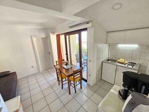A compact kitchen with a dining area, a small sink, and a coffee machine. - Holiday apartment with garden and air conditioning (Crikvenica)