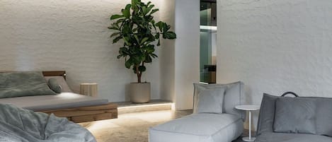 Une chambre moderne avec un lit, un canapé, une petite table et une plante en pot.