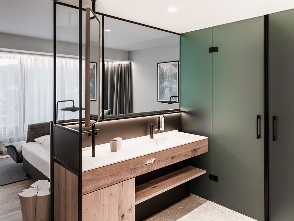 Een moderne slaapkamer met een houten wastafel, een grote spiegel en een groene garderobe.
