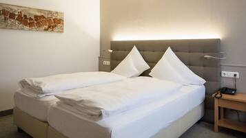 A hotel room with a double bed, a bedside table with a lamp, and a wall-mounted artwork.