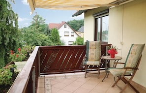 A balcony with a wooden fence, two chairs, a small table, and a potted plant. - Pet friendly apartment in Schleusingen (Schleusingen)