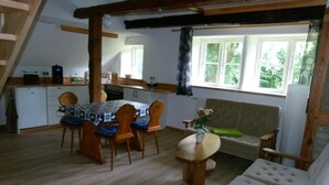 A cozy room with a dining table, chairs, a sofa, and a window with a view of greenery. - Apartment (DG) - Old rectory Rappin (Rappin)