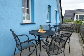 A blue building with a balcony featuring a round table and four chairs. - Apartment 2 - Apartments in Blu Hus (Kröslin)