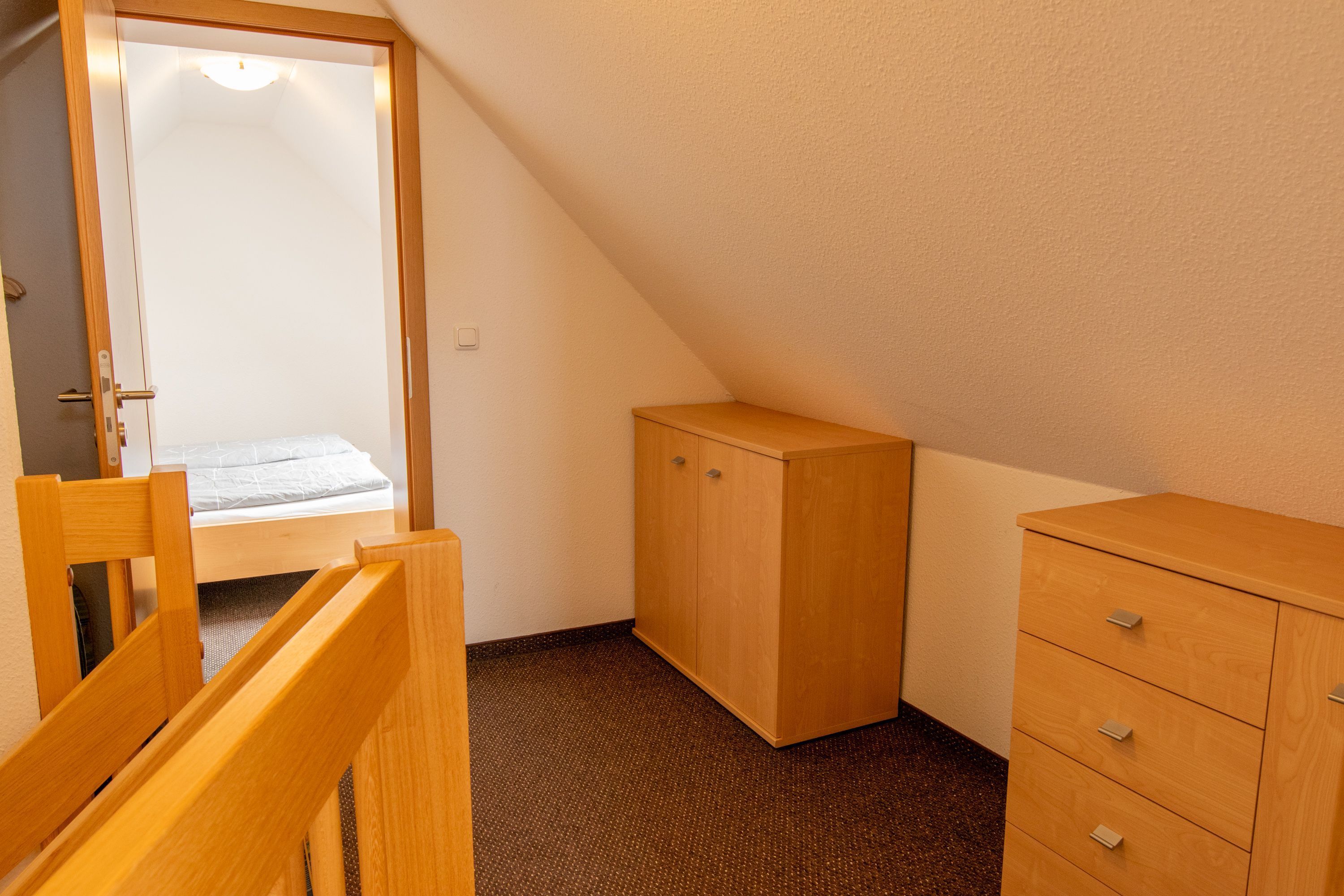 Une chambre à coucher comprenant un lit, une armoire en bois et une porte donnant sur une salle de bain.