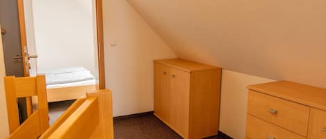 A bedroom with a bed, wooden wardrobe, and a door leading to a bathroom.