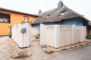 A house with a thatched roof, a mailbox, and a gated entrance.