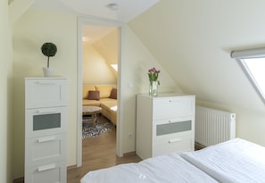 Ein Schlafzimmer mit Bett, Kommode, Heizkörper und Fenster.