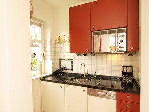 A compact kitchen with white cabinets, a black countertop, and a red upper cabinet. - PB-19 - Villa Park View Apt. PB-19 (Kühlungsborn)