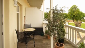 A covered porch with a table and chairs, a potted plant, and a view of the outdoors.