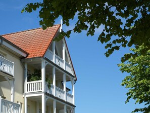 Een gebouw met twee verdiepingen, een rode pannendak en witte balkons.